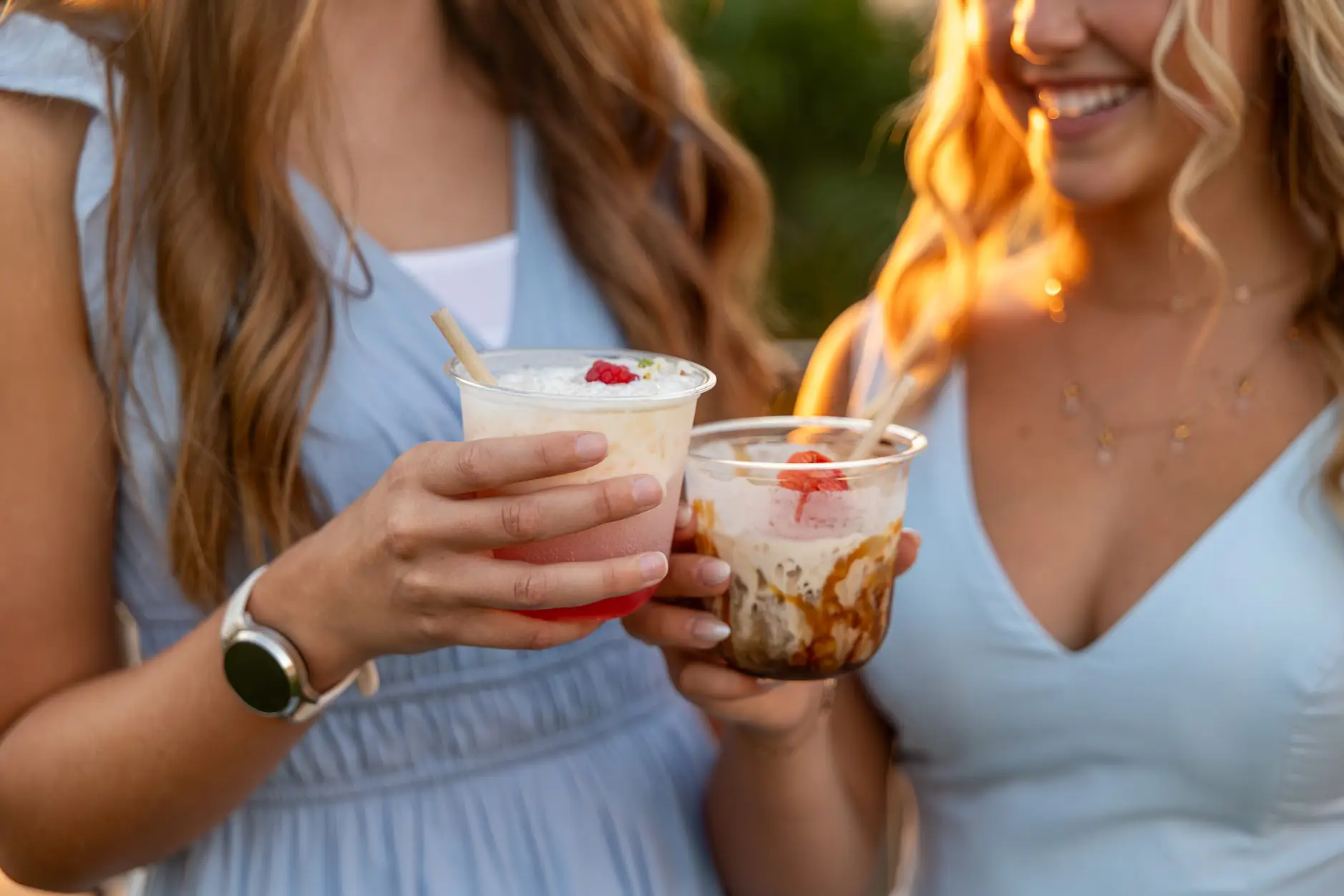 Two guests toasting with creamy dirty sodas topped with berries at golden hour