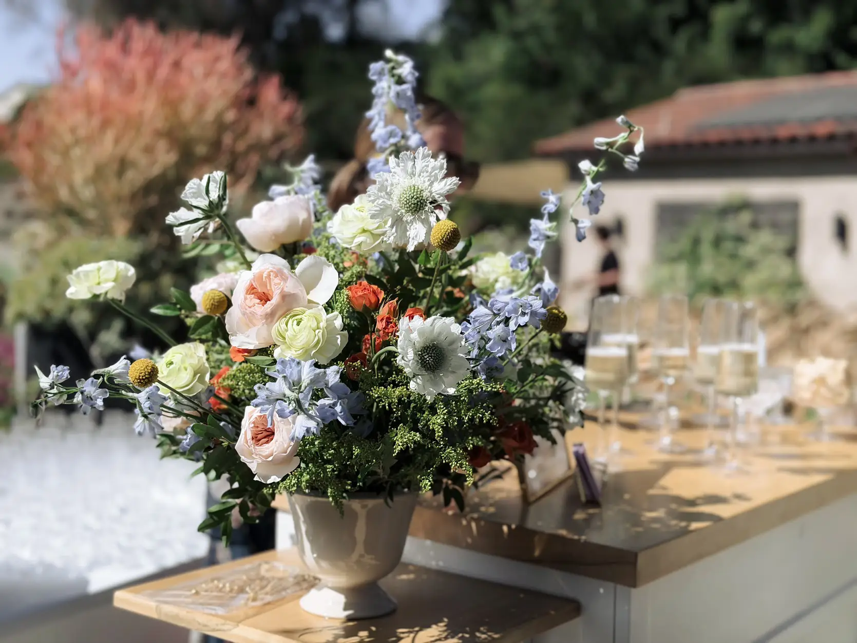 Designed floral arrangement with pastel roses, scabiosa, and delphinium on a mobile wedding bar in Orange County